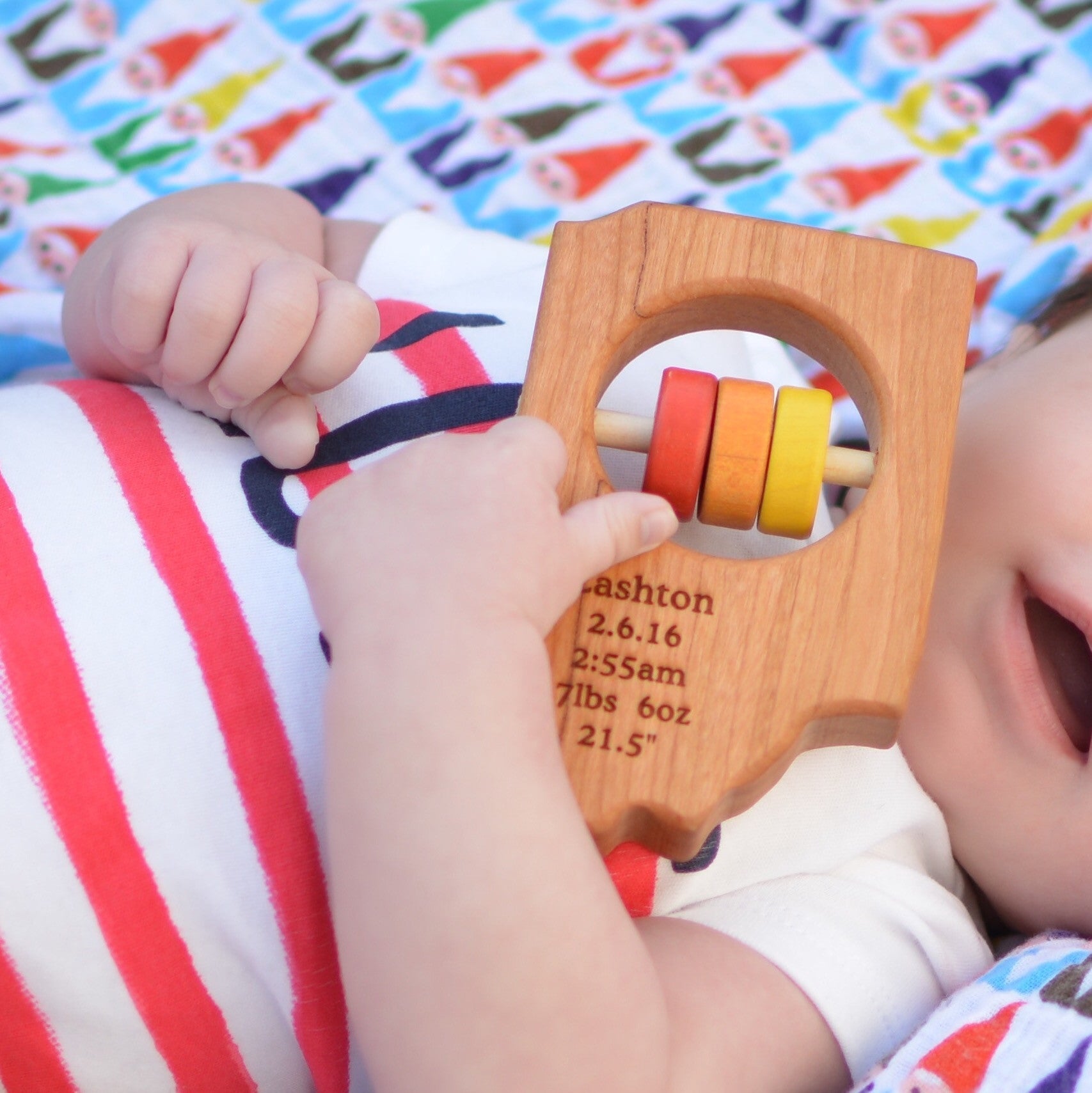 baby holding Indiana State Wooden Baby Rattle™ - Bannor-toys